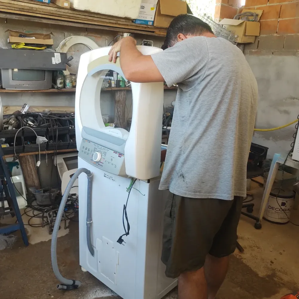 Técnico da Benassi trocando peças de uma máquina de lavar na oficina